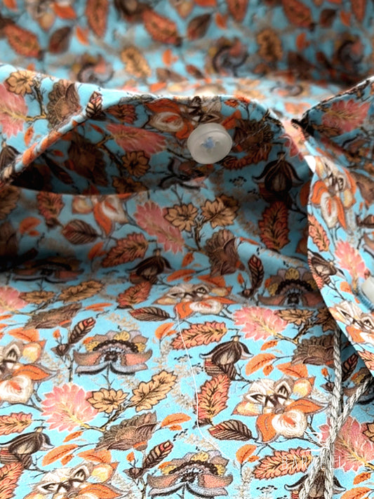 Camisa de algodón con estampado floral multicolor. Fondo azul claro con cuello italiano